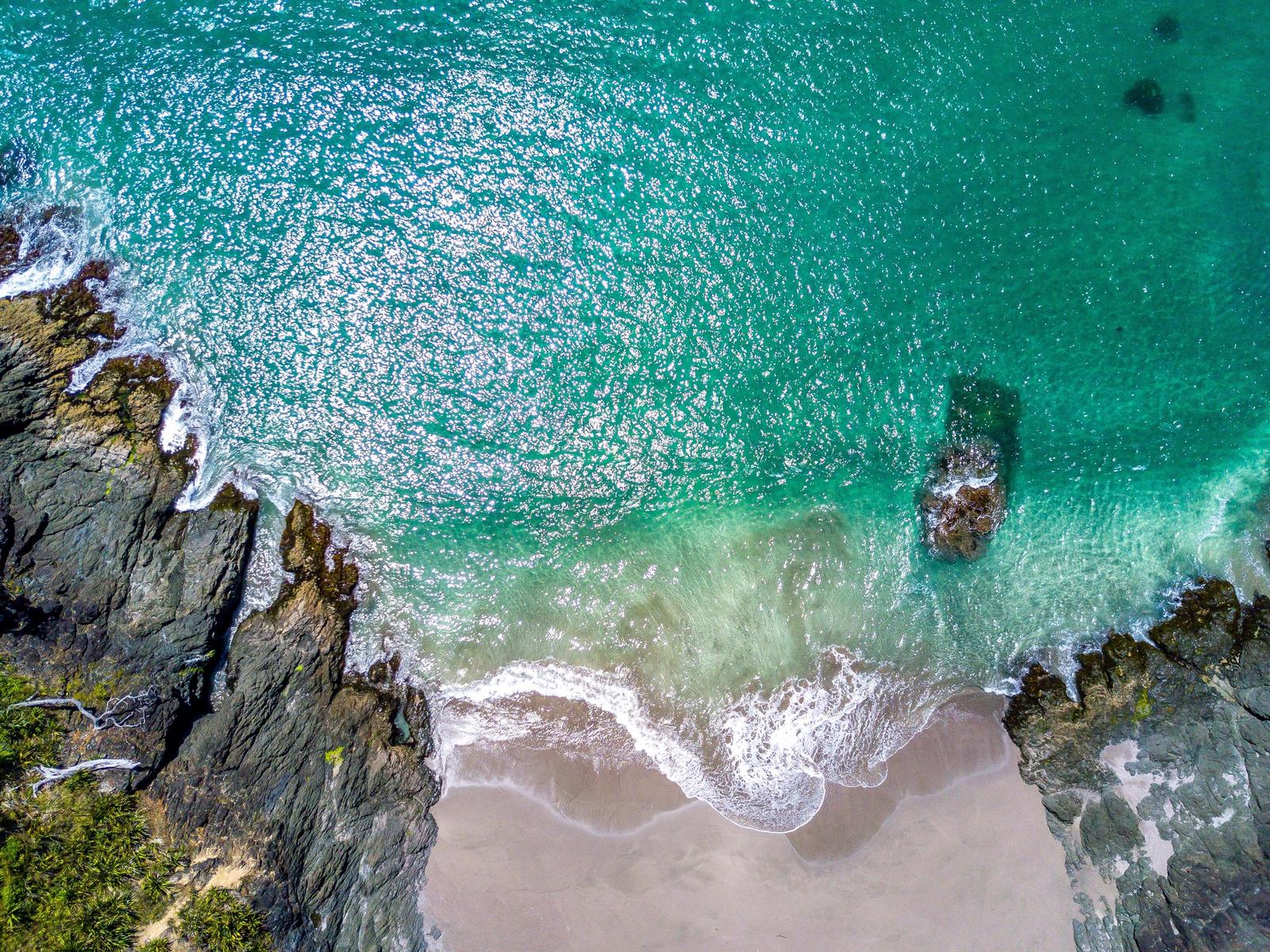 Aerial view of a beach with turquoise water and rocks